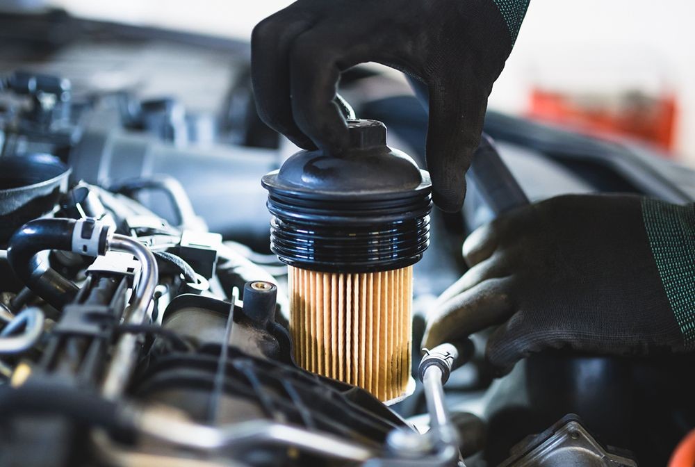 Replacing an automotive oil filter with a mechanic working under the vehicle.