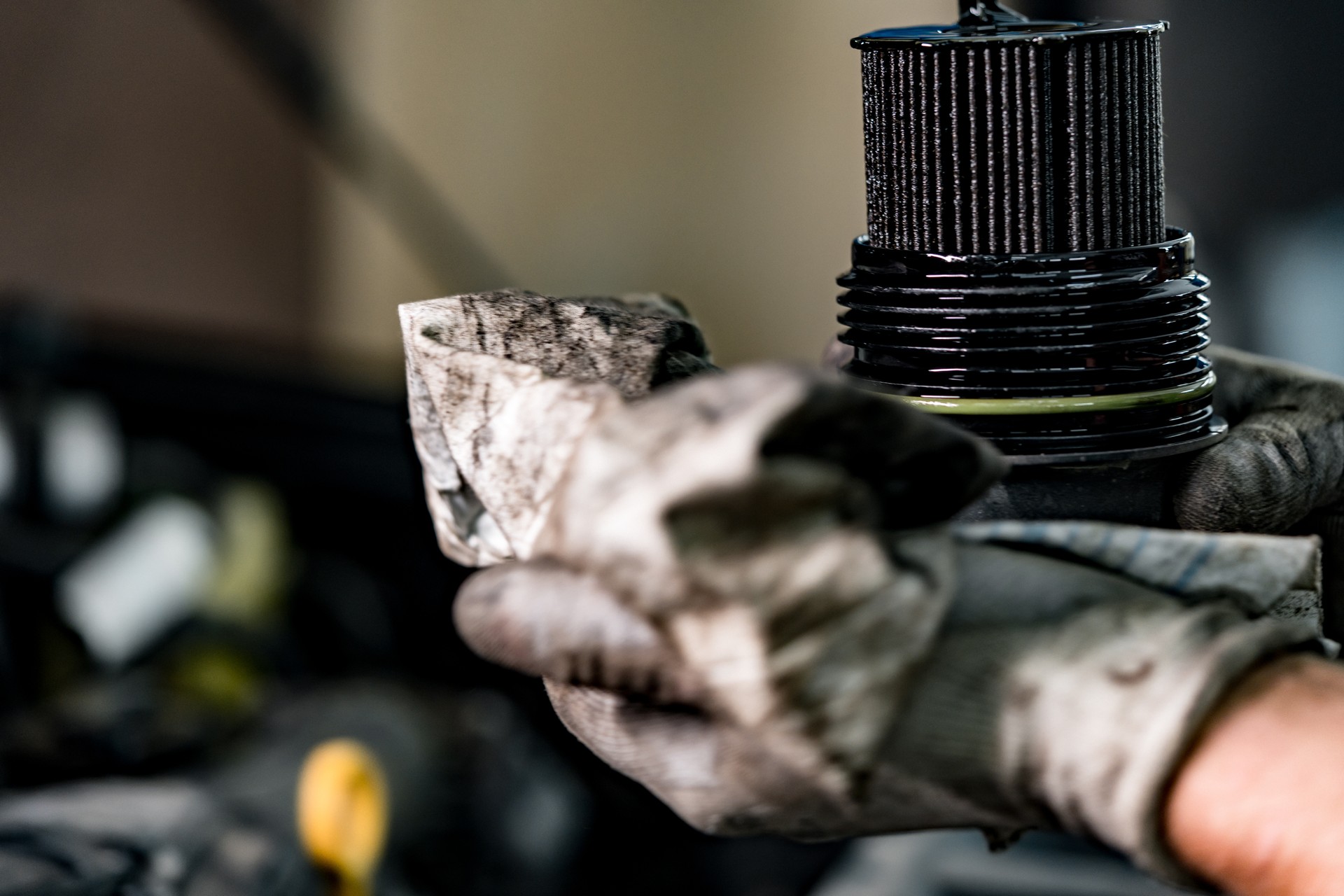 Hands of a repairman holding dirty car oil filter